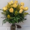 Yellow roses arranged in a clear glass vase with greenery