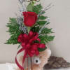 Two red roses in a silver vase with a teddy bear and ribbon