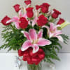 Bouquet of red roses and pink lilies in a glass vase with a red ribbon