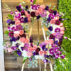 purple, pink, white flowers, and greenery. The standing cross includes the wood