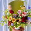 Colorful mixed flower arrangement in a white pedestal vase