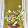 Mixed bouquet of peach roses and small white daisies in a white vase