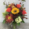 Mixed bouquet of roses, sunflowers, and chrysanthemums in a glass vase