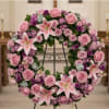 Pink and purple floral wreath on a black stand