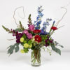 Mixed bouquet in a clear glass vase with red, purple, and blue flowers