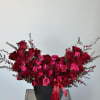 Red and pink rose arrangement in a black vase with ribbon