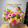 Large mixed flower arrangement in a woven basket with pink ribbon