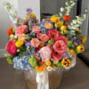 Layered pink and coral roses meet  pale blue hydrangeas in a