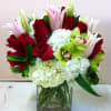 Bouquet of red roses, white hydrangeas, and green orchids in a glass vase