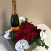 Red roses arranged with white orchids and a champagne bottle