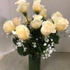 Cream roses arranged in a clear glass vase with small white filler flowers