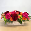 Rectangular floral arrangement with pink, red, and orange roses in a wooden box