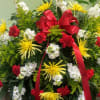 Large standing floral spray with red ribbon and yellow, white, and red flowers
