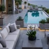 White orchids in a black pot on a modern patio beside a pool.