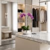 Purple orchids in a silver pot on a marble island in a modern closet