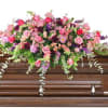 Pink and purple floral spray on a wooden casket