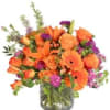 Orange and purple mixed bouquet in a glass vase