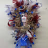 Door swag designed with ribbons, mesh and other Patriotic decor. Perfect for