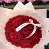 Bouquet of red roses wrapped in pale pink paper with a ribbon