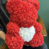 Red teddy bear made of rose-shaped flowers with a white heart on its chest