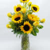 Sunflowers and yellow roses arranged in a clear glass vase