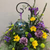 Purple and yellow floral arrangement with a glass ornament centerpiece