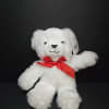 White teddy bear with a red ribbon bow on a black background