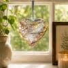 Heart-shaped glass ornament hanging in a sunlit window