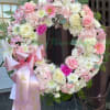 A soft pink and white sympathy wreath arranged on a sturdy metal