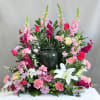 Large floral arrangement with pink, red, and white blooms in a dark vase