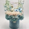 Blue and white floral arrangement in a round hatbox with a small teddy bear