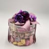Gift box with purple flowers and chocolates in a clear round container