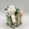 Gift box topped with white and teal flowers and satin ribbons