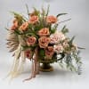 This luxurious arrangement features warm mocha and blush roses, lush greenery, and