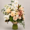 A luxurious floral arrangement featuring elegant white orchids, blush and champagne roses