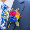 Colorful boutonniere with roses and a blue flower on a suit lapel