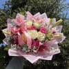 Pink and white bouquet of roses and lilies wrapped with a pink ribbon