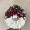 Circular floral wreath with red roses and white chrysanthemums on a stand