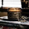 Amber glass candle jar with a black label on a tray