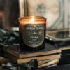 Lit amber candle in a glass jar on stacked books
