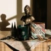 A candle, decorative bust, and New Orleans box arranged on a table