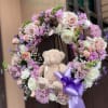A plush teddy bear nestled at the heart of a round sympathy