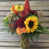 Colorful mixed bouquet in a glass vase with sunflowers and dahlias
