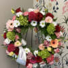 Heart-shaped floral wreath with roses, daisies, and carnations on an easel