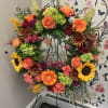 Designers choice of seasonal harvest colors arranged in a wreath to surround