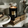 Lit black candle in a glass jar on stacked books