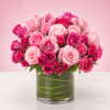 A lush cluster of blush and magenta roses, lilies, spray roses, and