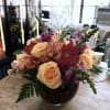 Peach roses and pink orchids mingle with red gerbera daisies in a
