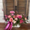 Pink floral arrangement with roses and daisies in a white container
