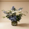 Blue and white arrangement with roses, mums, and hydrangeas in a clear glass cylinder vase